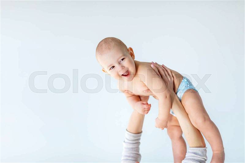 Side view of mother holding adorable baby boy above the head isolated on gray, 1 year old baby concept, stock photo