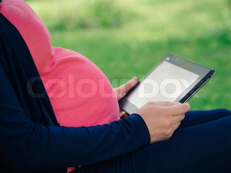 Pregnant woman with tablet e-reader, stock photo