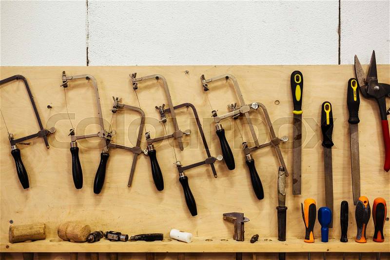 Background shot of various woodworking tools hanging on board wall in workshop, stock photo