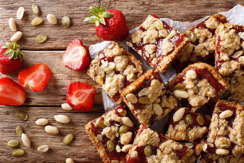 Oat bars with strawberries, seeds and nuts close-up on the table. horizontal view from above , stock photo