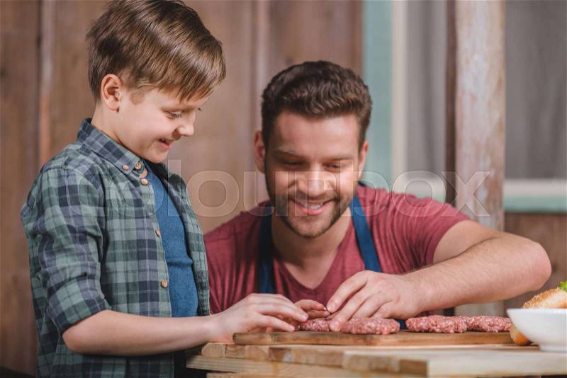 Happy father and son cooking meat patties together, dad and son cooking concept, stock photo