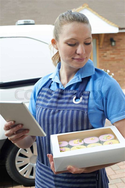 Baker With Digital Tablet Making Home Delivery Of Cupcakes, stock photo
