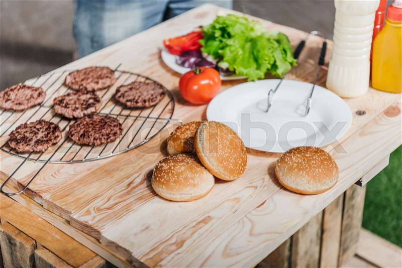 Close up view of various burgers ingredients on wooden table, stock photo