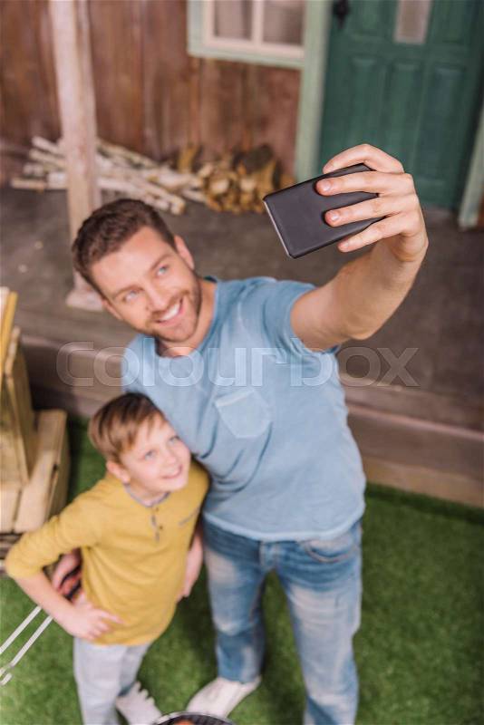 High angle view of smiling father and son taking selfie, stock photo