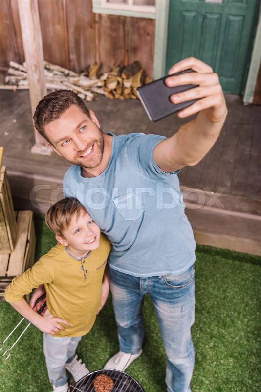 High angle view of smiling father and son taking selfie, stock photo