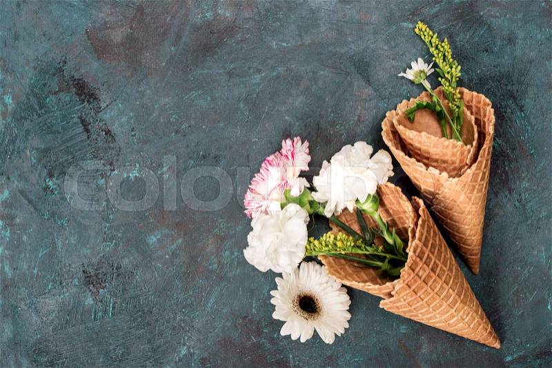 Top view of flowers in sugar cones laying on stone table, still life, stock photo