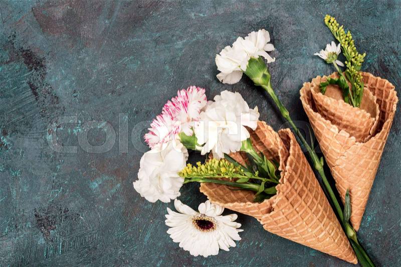 Top view of flowers in sugar cones laying on stone table, still life, stock photo