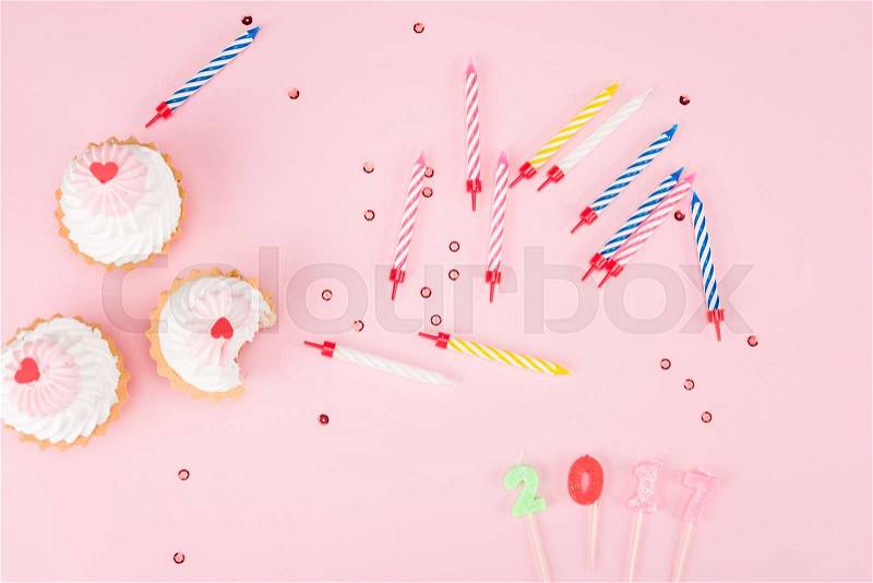 Top view of cakes, colorful candles and 2017 sign on pink, birthday party concept, stock photo