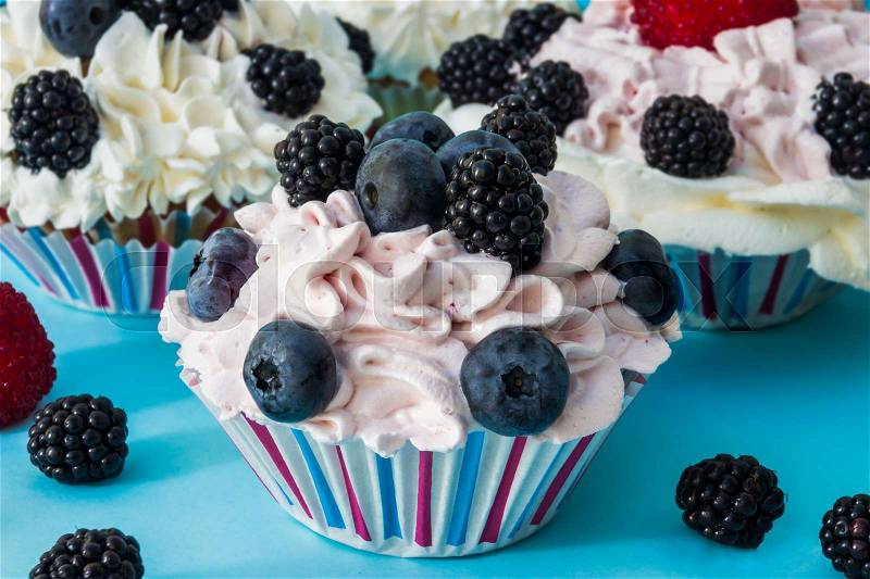 CUPCAKES WITH CREAM AND BERRIES, stock photo