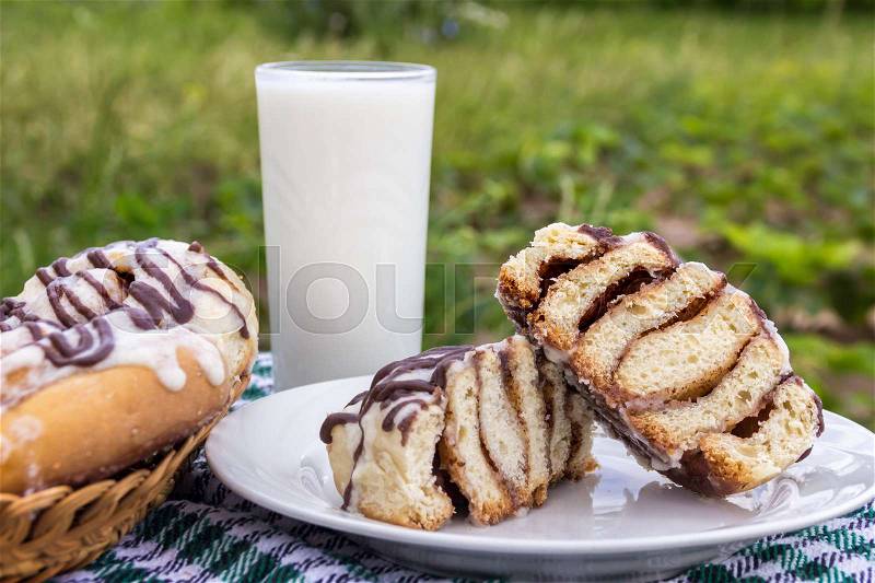 Homemade cinnabons cinnamon buns with cream cheese glaze and chocolate icing and glass of milk, stock photo