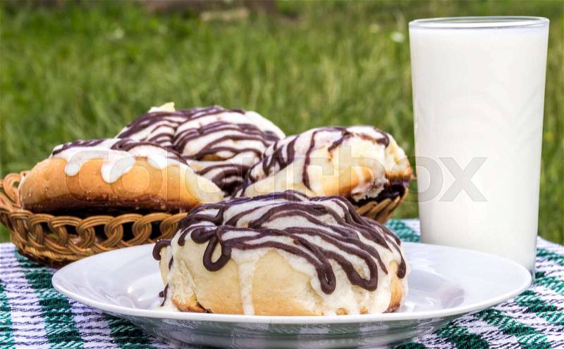 Homemade cinnabon cinnamon buns with cream cheese glaze and chocolate icing and glass of milk, stock photo