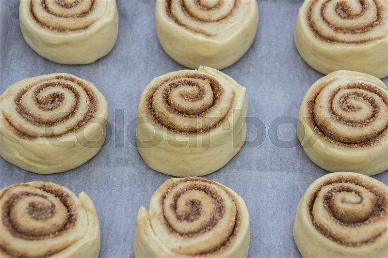 Beautiful and uncooked cinnamon buns with cinnamon, stock photo