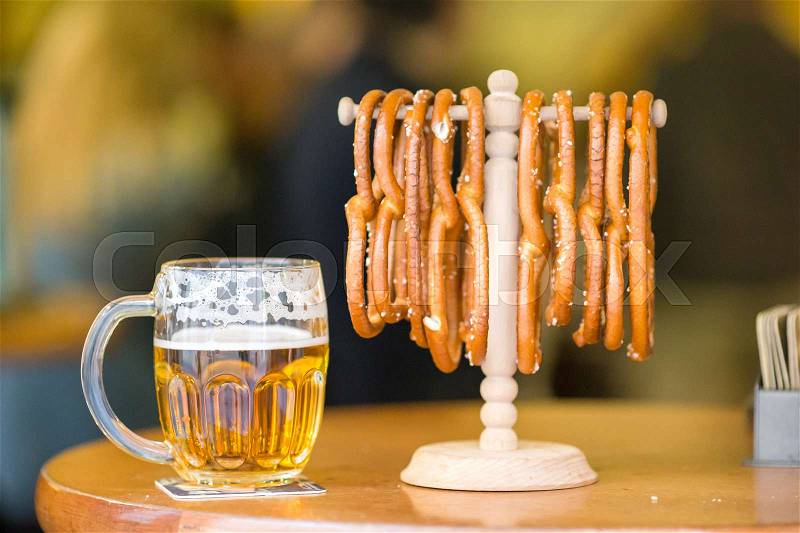 Close up salted soft pretzels and beer on wooden background, stock photo