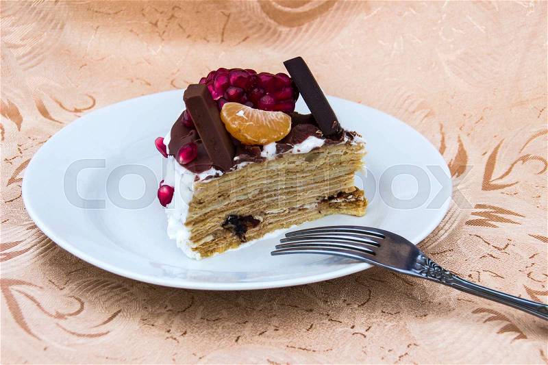 Piece of honey cake with chocolate and fruits, stock photo