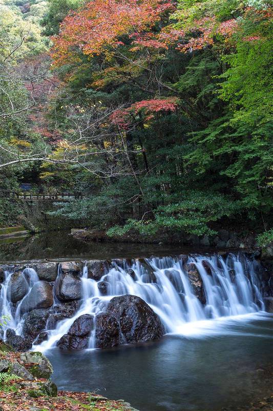 River wier with overflowing water from Minoh (Mino-o) waterfall in autumn, Osaka, Japan, stock photo
