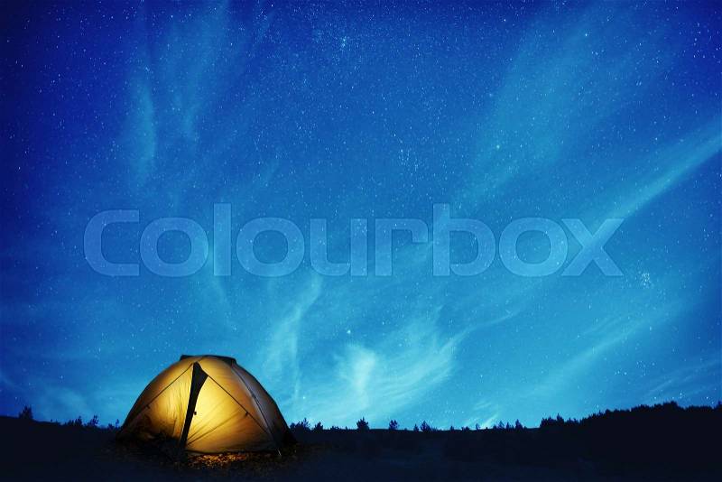 Illuminated yellow camping tent under many stars and at night, stock photo