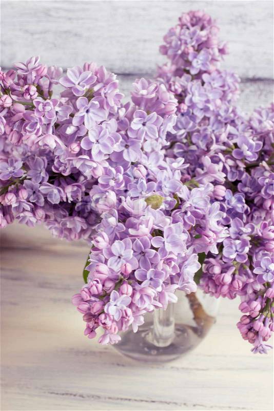 Lilac flowers in a glass bottle on shabby wooden board, stock photo