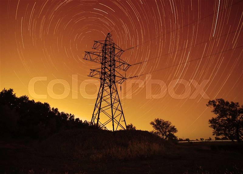 Space energy: transmission tower against star trails in night sky, stock photo
