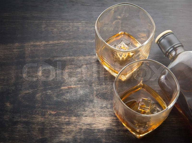 Glass with ice cubes and whiskey bottle on wooden table,top view, stock photo