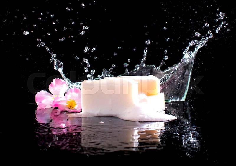 Soap bar with splashes of water on the dark background, stock photo