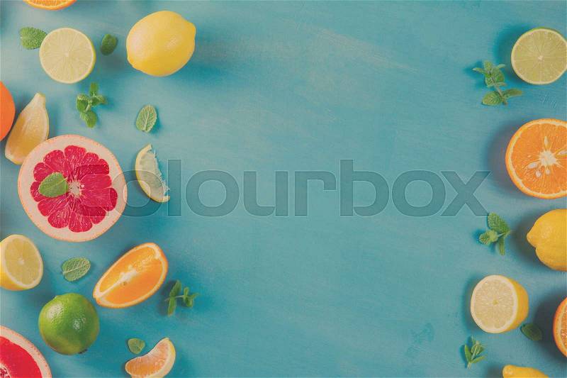 Citrus food frame pattern on blue background - assorted citrus fruits with mint leaves, retro toned, stock photo