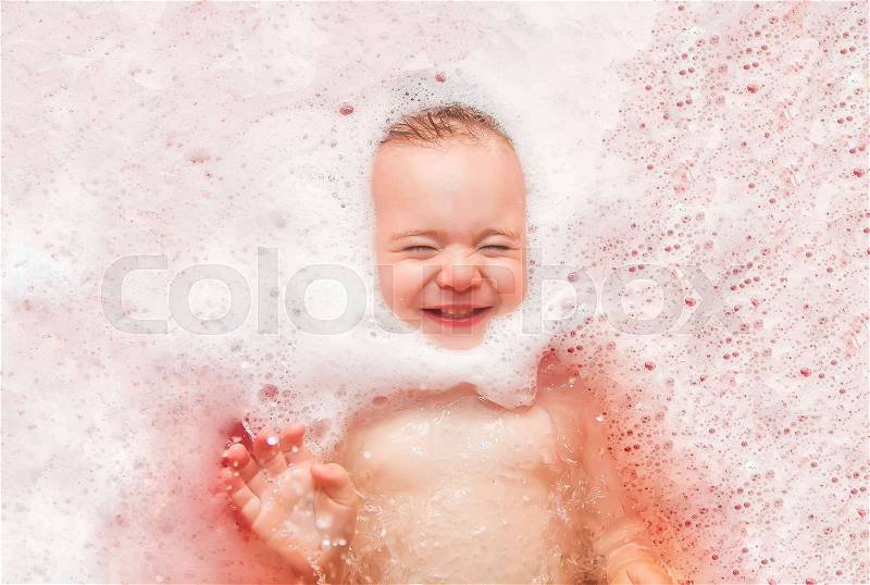 Happy baby in the bath, swimming in the foam. Baby shower, stock photo