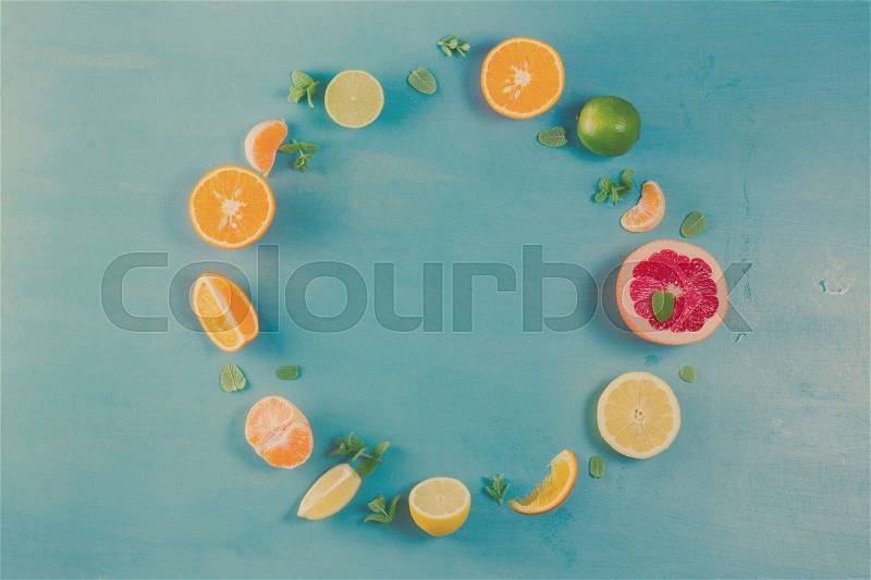 Citrus food circle frame pattern on blue background - assorted citrus fruits with mint leaves, retro toned, stock photo