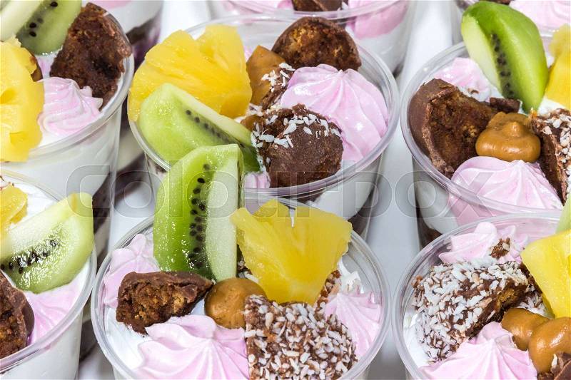 Trifle (cake in glass), chocolate biscuit cakes with cream cheese and blueberry jam, decorated with meringue, fruit (kiwi and pineapple) and candy, stock photo