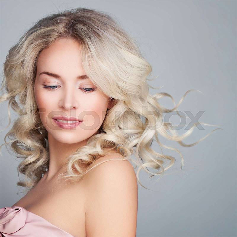 Beautiful Blonde Woman with Blowing Blonde Curly Hair. Fashion Model with Wavy Hairstyle, stock photo