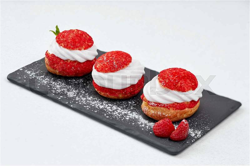 French Cakes with strawberry cream shanti. aery Strawberry brewing cake on black shale. Restaurant composition on white background, stock photo