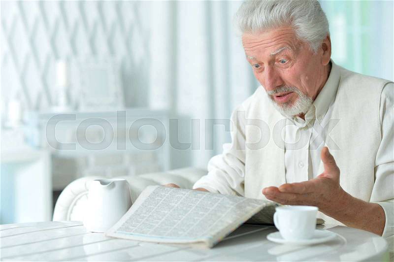Portrait of an elderly man reading a newspaper, stock photo
