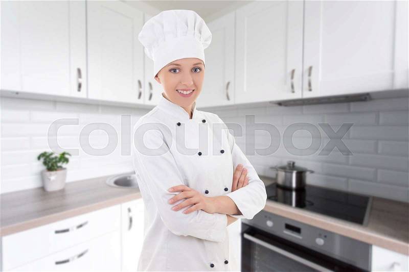 Young happy chef woman in uniform posing in modern kitchen, stock photo