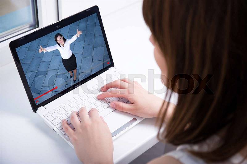Young woman watching business video blog on laptop at home, stock photo