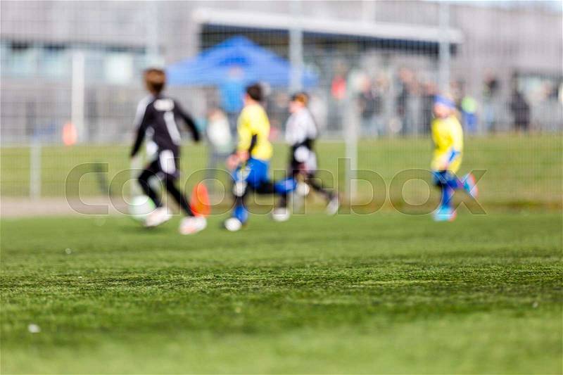 Blur of young kids playing a youth soccer match outdoors on an green soccer pitch, stock photo