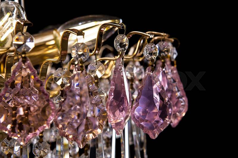 Large crystal chandelier with pink crystals details isolated on black background. Luxury royal expensive chandelier for living room, Hall of celebration, stock photo