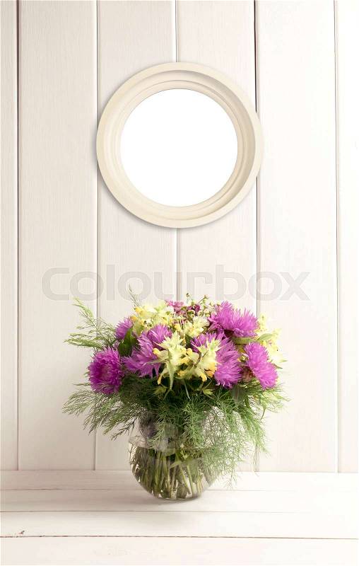 Flower bouquet in glass round vase and round frame on background of white wooden planks in provence style. Home interior. Empty place for photo or text. Copy space, stock photo