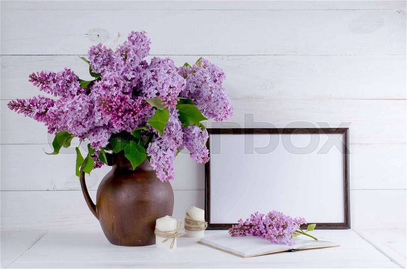Lilac bouquet in clay jug with motivational frame for your text or picture on background of white wooden planks in scandinavian style, stock photo