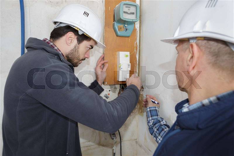 Builders checking electrical panel indoors, stock photo
