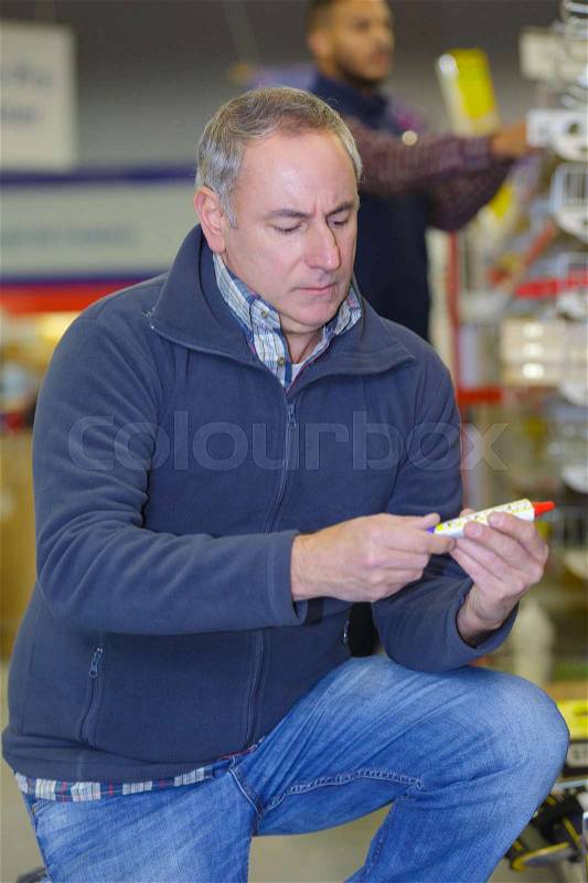 Man customer picking sealing component in household shop, stock photo