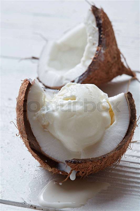 Vanilla coconut ice cream in shell of coconut on a wooden white background, stock photo