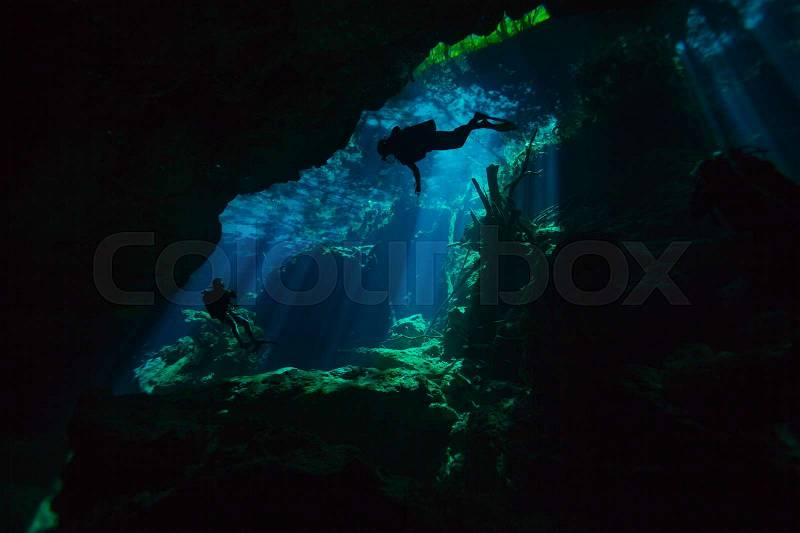 Two divers exploring hidden reefs in the cenote underwater cave of Quintana roo, Mexico, stock photo