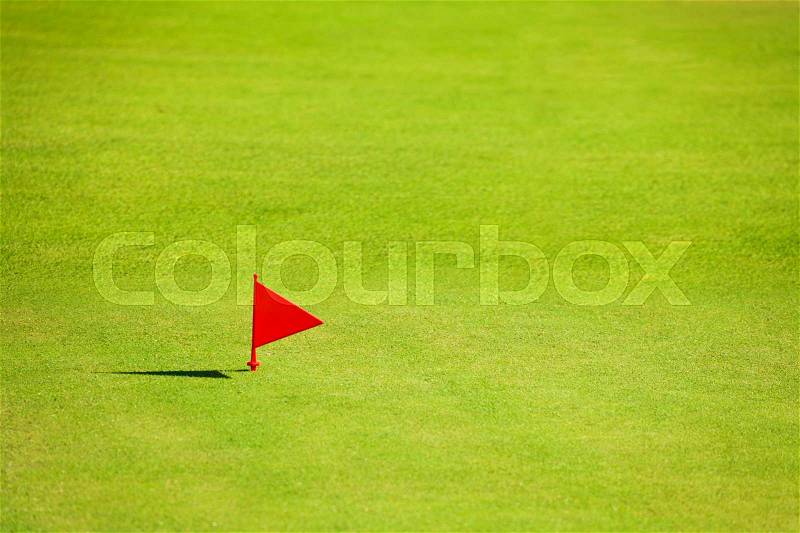 Putting green with red flag marker at end of fairway on the golf course , stock photo