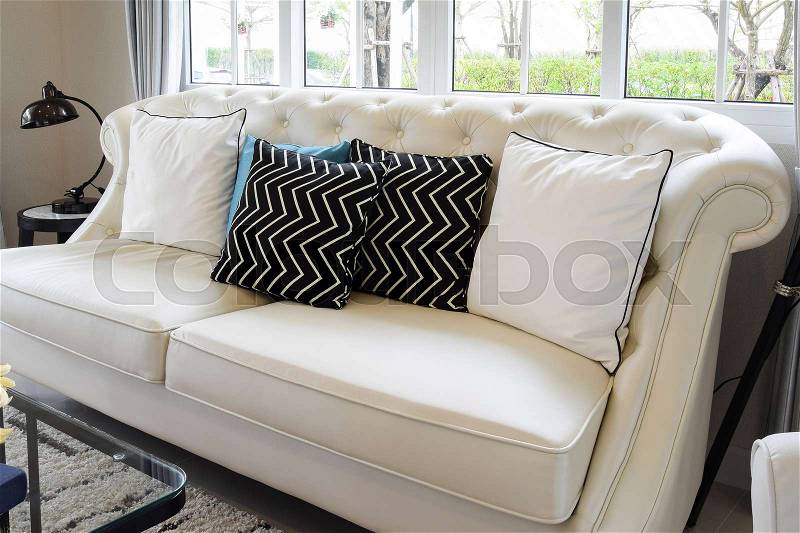 White and blue pillows on a white leather couch in vintage living room, stock photo