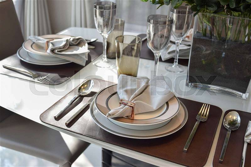 Elegant table set in modern style dining room interior, stock photo