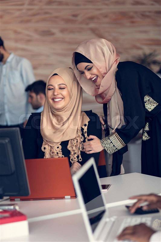 Two woman with hijab working on laptop in office, stock photo