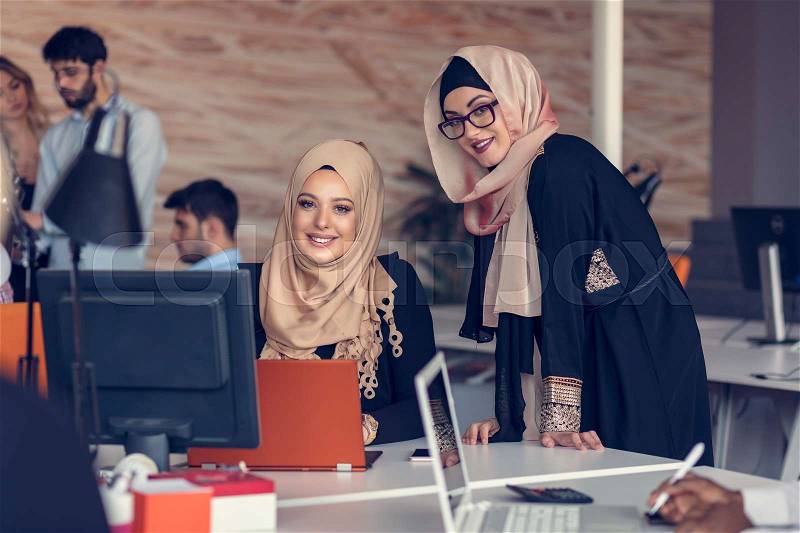 Two woman with hijab working on laptop in office, stock photo