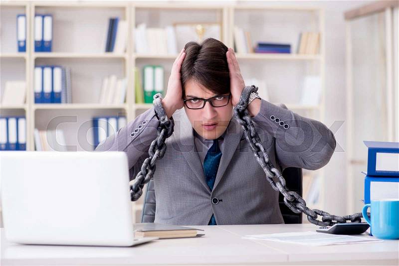Businessman tied with chains to his work, stock photo