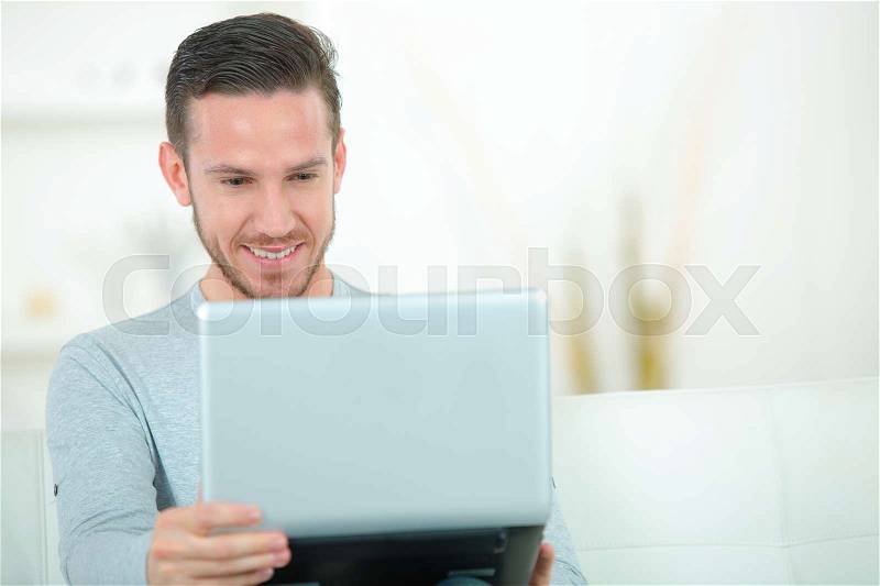 Happy man with laptop indoors, stock photo