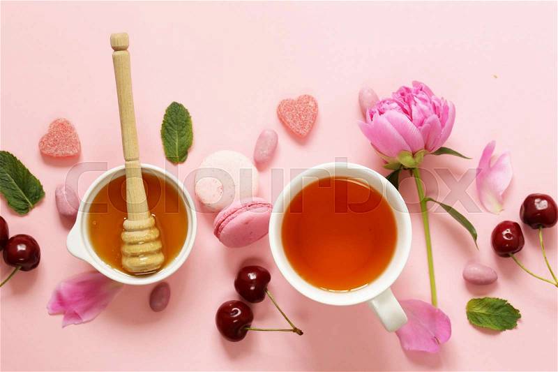 A cup of tea for a woman, macaroon, flowers and sweets on a pink background, stock photo