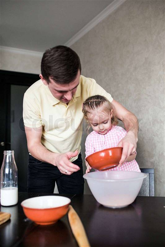Dad and little daughter in the kitchen play together with flour, stock photo
